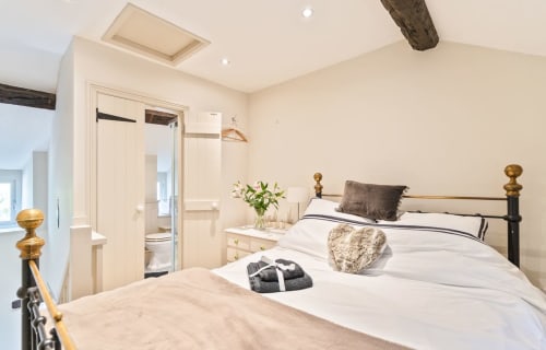 Modern bedroom in Cosy Llangattock Hideaway cottage, Crickhowell, with en-suite bathroom and brass bed frame