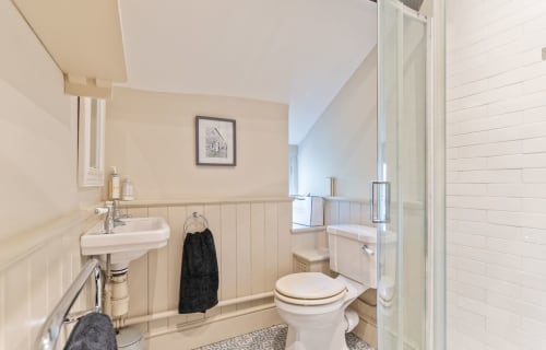 Bathroom in Cosy Llangattock Hideaway cottage, Crickhowell featuring white sink, toilet, and shower enclosure with beige