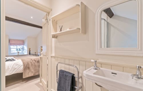 Modern en-suite bathroom with white sink, mirror, and heated towel rack at Cosy Crickhowell Cottage, Crickowell