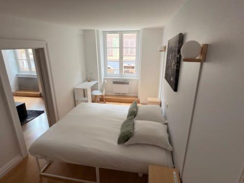 Chambre moderne et lumineuse avec lit blanc, bureau et miroir en pied à l'appartement Hôtel Saint Christophe Belfort.