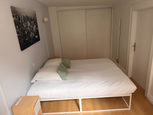 Chambre lumineuse à l'Hôtel Saint Christophe avec lit blanc, plaid vert, art urbain et placard coulissant