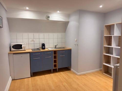 Kitchenette moderne dans un studio à l'Hôtel Saint Christophe, Belfort, avec armoires bleues, micro-ondes et évier