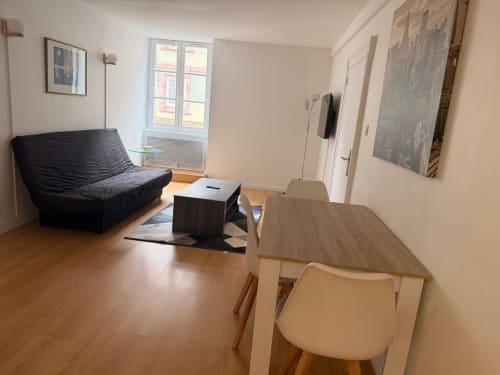 Studio moderne à l'Hôtel Saint Christophe Belfort avec canapé noir, table à manger, parquets et lumineux