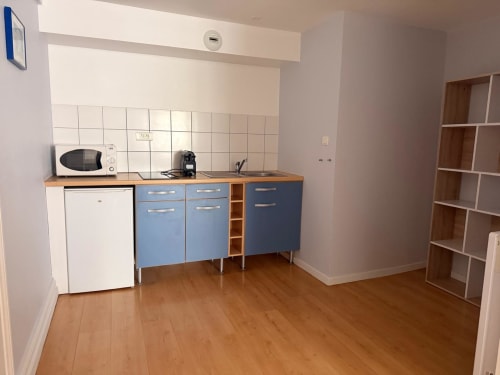 Kitchenette moderne dans un appartement de Belfort avec armoires bleues, micro-ondes et comptoirs en bois