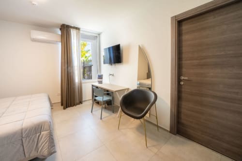 Camera moderna dell'Hotel Belvedere Resort con letto singolo, scrivania, TV e balcone con vista montagna a Castellammare del Golfo