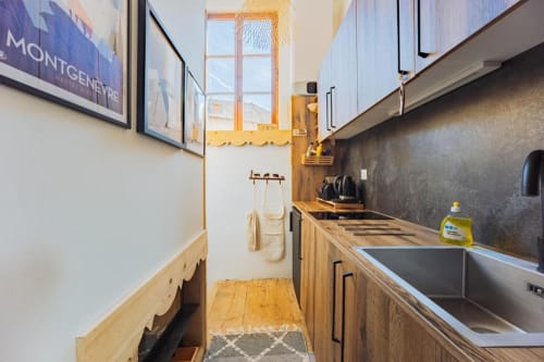 Cuisine moderne de l'appartement Cocon De Roussillon avec meubles en bois, évier en inox et vue sur la ville