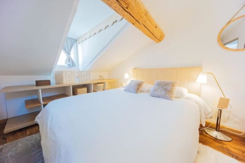 Chambre mansardée lumineuse au Cocon De Roussillon avec poutres apparentes, velux, literie blanche et mobilier contemporain