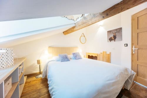 Chambre mansardée lumineuse au Cocon De Roussillon avec puits de lumière, poutres bois et équipements modernes