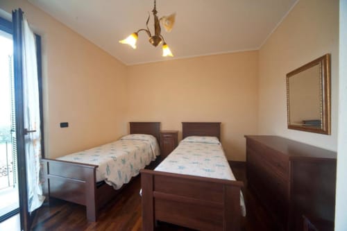 Camera doppia con letti in legno e pareti beige nell'appartamento L'Elce presso l'Agriturismo Buriano, Lubriano