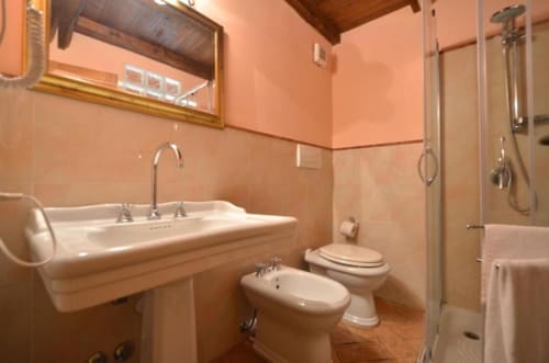 Bagno dell'appartamento La Quercia, Agriturismo Buriano, con piastrelle color pesca, doppio lavabo, bidet, WC e doccia