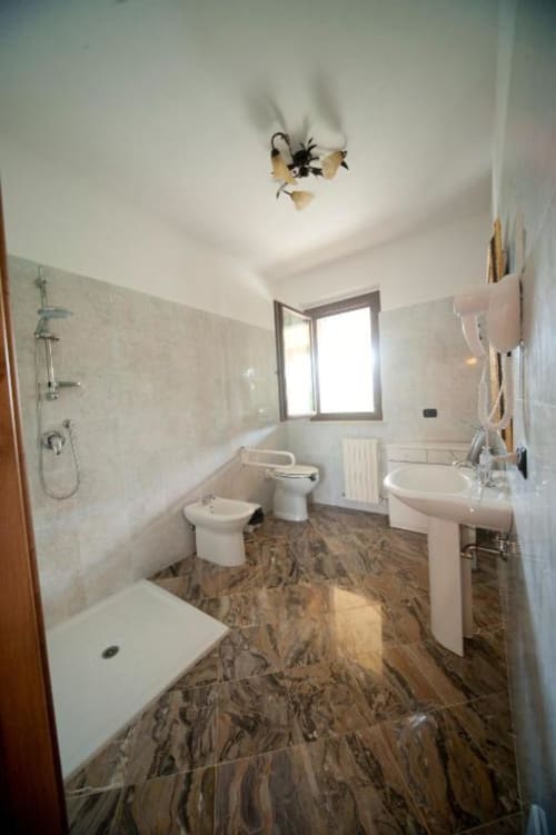 Bagno moderno nell'appartamento L'Elce presso l'Agriturismo Buriano, con pavimento in marmo, wc, bidet, lavabo su piedistallo e