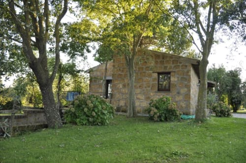 Casale in pietra circondato da alberi e prato presso l'Agriturismo Buriano a Lubriano, Italia, con vista sul giardino e zona coperta