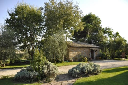 Rustico casale in pietra circondato da alberi alti e giardini curati all'Agriturismo Buriano di Lubriano, Italia