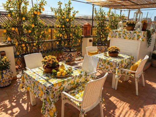 Terrazza a tema limoni presso Spagna Lemon Suites Roma con alberi da frutto, fiori gialli e zona pranzo