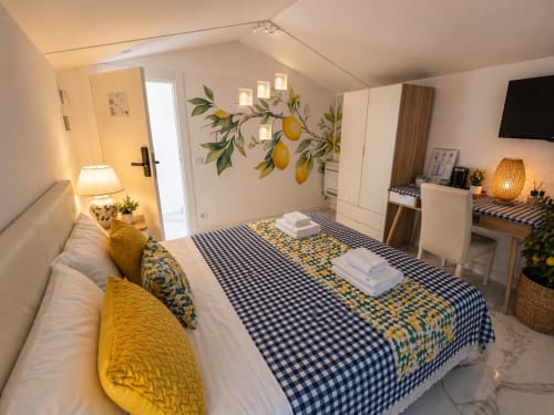 Suite Deluxe Queen Spagna Lemon a Roma con accenti gialli, arte murale a limoni, biancheria blu gingham, servizi moderni