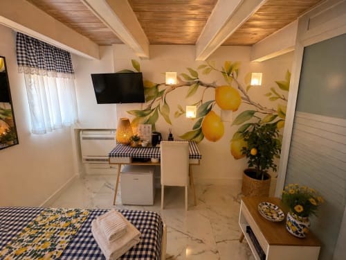 Suite Deluxe Spagna Lemon Suites Roma con murale di limoni, dettagli blu a scacchi, TV, scrivania e pavimenti in marmo