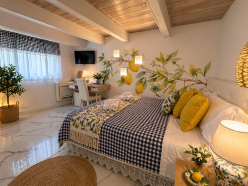 Suite Deluxe Spagna Lemon Suites a Roma con dipinto di limoni, lenzuola blu gingham, cuscini gialli, travi in legno e
