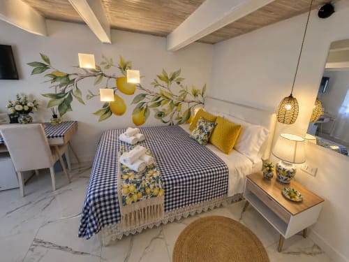Suite Superior Spagna Lemon Suites a Roma con biancheria a quadretti blu, opere d'arte limone gialle, travi in legno a soffitto, e