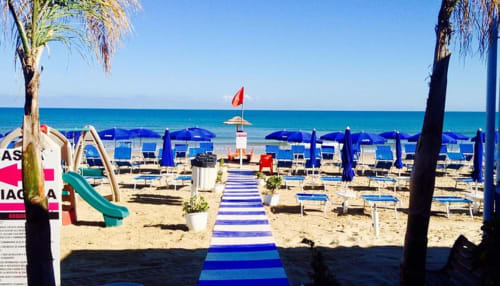 Spiaggia del Resort Hotel Belvedere a Castellammare del Golfo con ombrelloni blu, lettini e vista sul mare