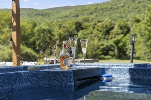 Luxury poolside lounge at Malkita Homes Highland Mills with champagne glasses, mountain views, and serene landscape backdrop.