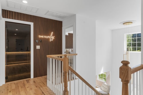 Modern spa hallway at Malkita Homes Highland Mills with wood paneling, sauna door, neon relax sign