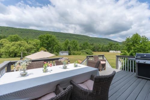 Deck at Malkita Homes in Highland Mills with dining table, wicker chairs, grill, and mountain views
