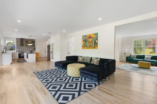 Modern open-concept living room at Malkita Homes in Highland Mills with black sectional sofa, patterned rug, and contemporary