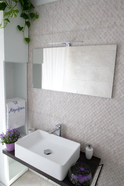 Bagno moderno presso l'Exclusive Domus Gaudia Rome con lavabo rettangolare bianco, ampio specchio, pareti in piastrelle beige texture e
