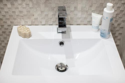 Moderno lavabo del bagno con rubinetto cromato, dispenser di sapone e articoli da toilette all'hotel Exclusive Domus Gaudia Roma