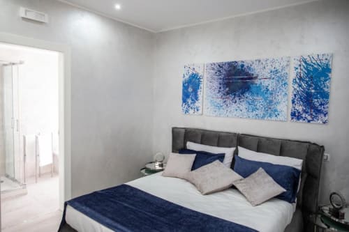 Camera moderna presso Exclusive Domus Gaudia Roma con letto imbottito grigio scuro, biancheria blu navy e arte astratta blu alle pareti