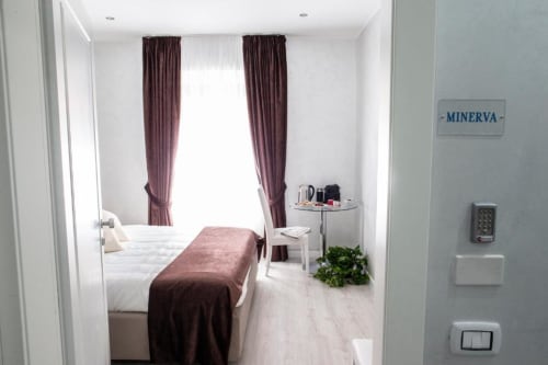 Superior King Room at Exclusive Domus Gaudia Roma with burgundy curtains, white bedding, and city view