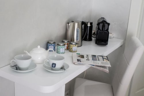 Zona bevande in camera d'albergo con teiera, tazze, bollitore, caffettiera e giornali presso Domus Gaudia Roma