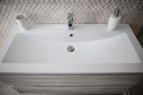 Modern white bathroom sink with dual faucet at Exclusive Domus Gaudia hotel in Rome, Italy