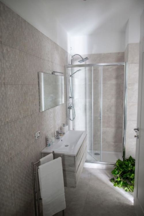 Modern bathroom in Superior King Room at Exclusive Domus Gaudia Roma, featuring glass shower enclosure, white sink, and tiled