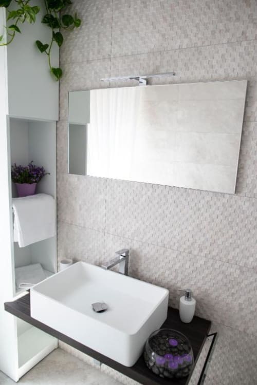 Moderno mobile bagno con lavabo rettangolare bianco, ampio specchio e pareti piastrellate all'hotel esclusivo Domus Gaudia Roma