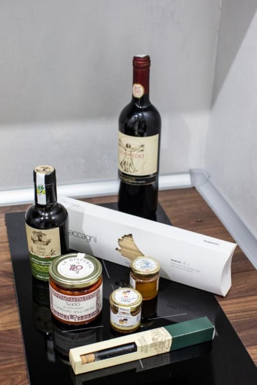Esclusivo set regalo gourmet italiano presso Domus Gaudia Roma: vino, olio d'oliva e prodotti artigianali su display nero