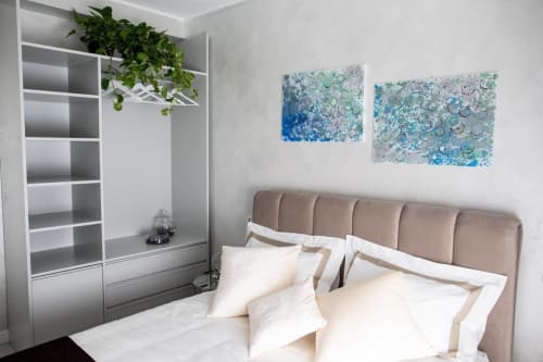 Camera moderna a Domus Gaudia Roma con testata beige, biancheria bianca, mobile contenitore e arte murale astratta blu