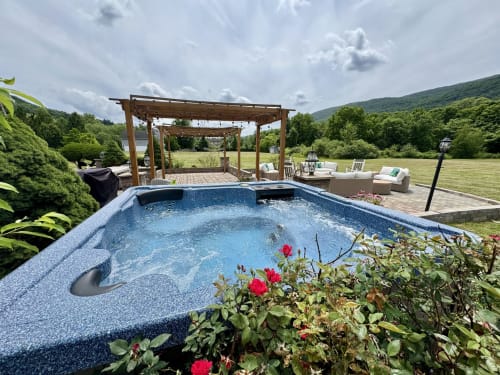 Luxury backyard pool with hot tub, wooden pergola, and mountain views at Malkita Homes in Highland Mills