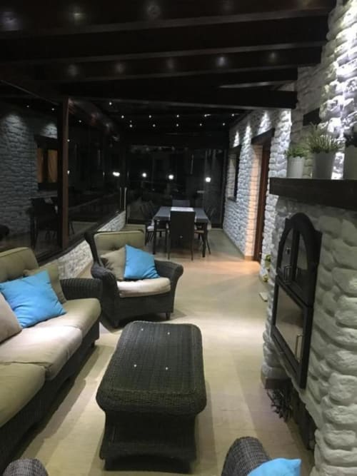 Hotel Mulhacén Trevélez glazed terrace with seating area, fireplace, and dining space at night