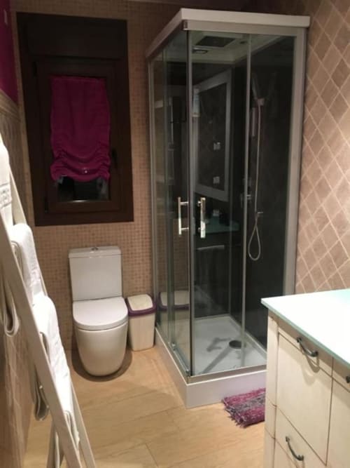 Modern bathroom in Hotel Mulhacén Trevélez with glass shower enclosure, white toilet, and vanity sink