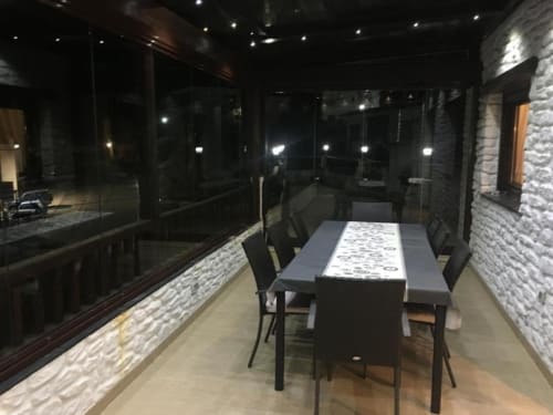 Modern dining area in glazed terrace at Hotel Mulhacén Trevélez, Granada with stone walls and night views