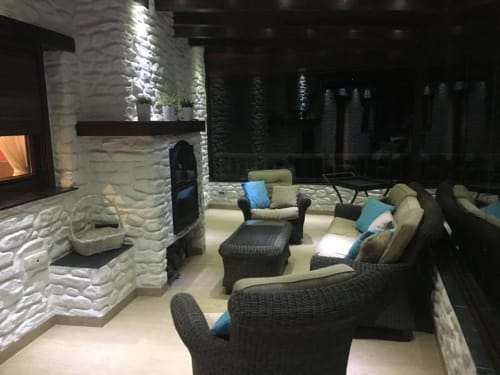 Apartment lounge at Hotel Mulhacén with wicker seating, fireplace, terrace views, and blue accent pillows