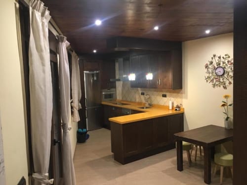 Modern kitchen and dining area in Apartment 2 at Hotel Mulhacén Trevélez, Granada, featuring dark cabinetry, yellow