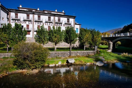 Hotel Mulhacén Trevélez in Granada with riverside garden, ivy-covered trees, and mountain views under blue sky