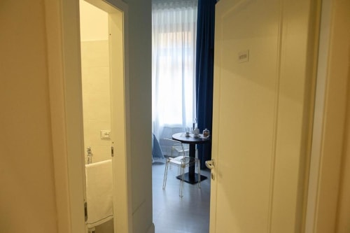 Hallway entrance to Deluxe King Room at Exclusive Domus Gaudia Roma, with yellow walls and view to dining area