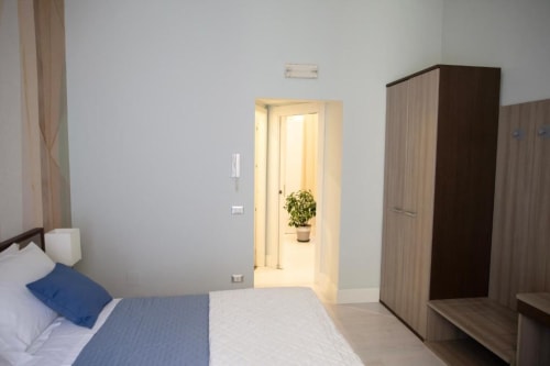 Camera moderna presso Exclusive Domus Gaudia a Roma con letto, armadi in legno e accesso al cucinotto