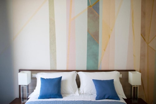Camera Executive Suite moderna presso Domus Gaudia Roma con cuscini blu, biancheria bianca e arte astratta con righe