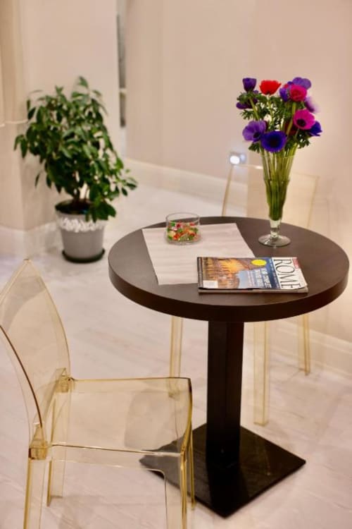 Moderna zona soggiorno nella cottage Pia Domus di Domus Gaudia Roma con tavolo scuro rotondo, anemoni colorati, pianta in vaso e