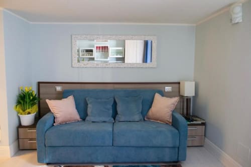 Elegante zona living nella cottage Pia Domus di Exclusive Domus Gaudia Roma, con divano blu e cuscini rosa
