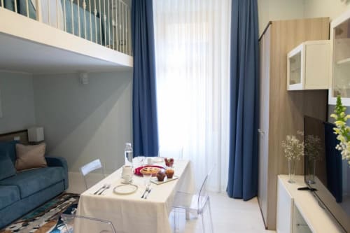 Studio moderno presso Exclusive Domus Gaudia Roma con tavolo da pranzo, divano, angolo cottura e camera in soppalco